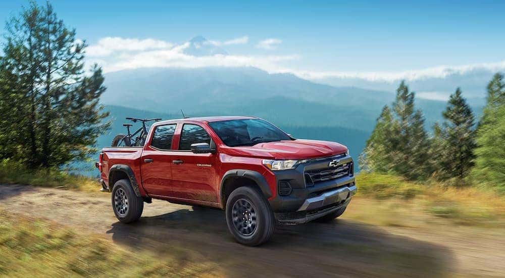 A red 2024 Chevy Colorado driving on a mountain path with bikes in the back.