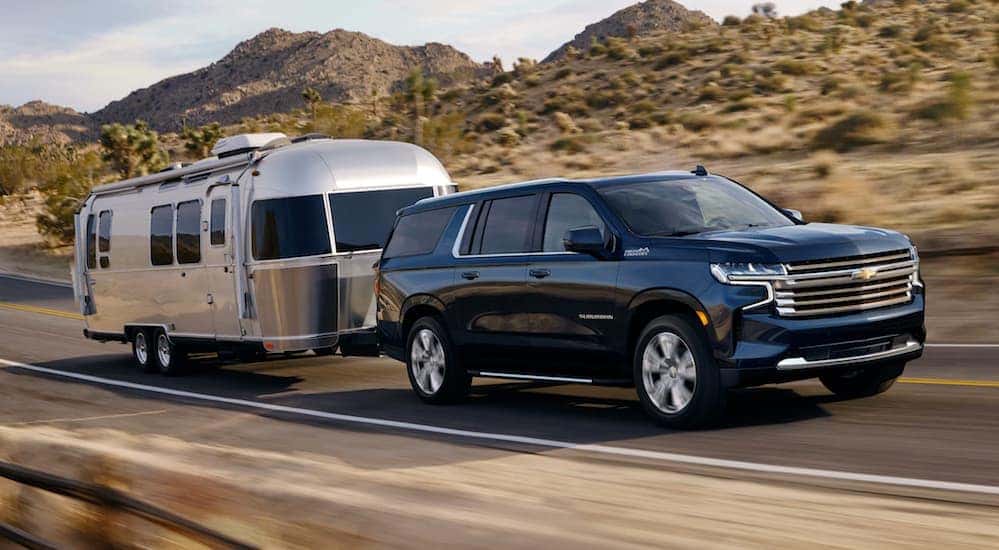 A black 2021 Chevy Suburban towing an airstream trailer.