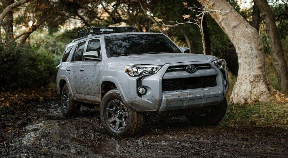 A grey 2021 Toyota 4Runner off-roading through mud in the woods.