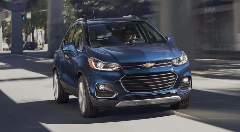 A blue 2020 Chevy Trax is shown driving in a city.