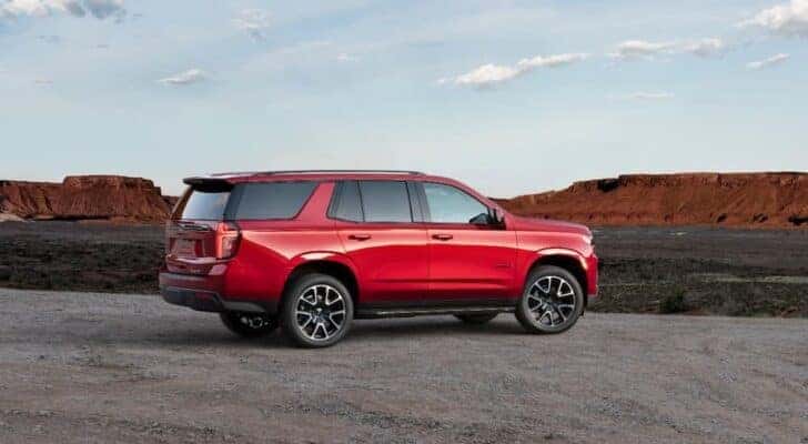 One of the best used SUVs for sale near Troy, a red 2021 Chevy Tahoe RST, is shown from a side angle while parked.