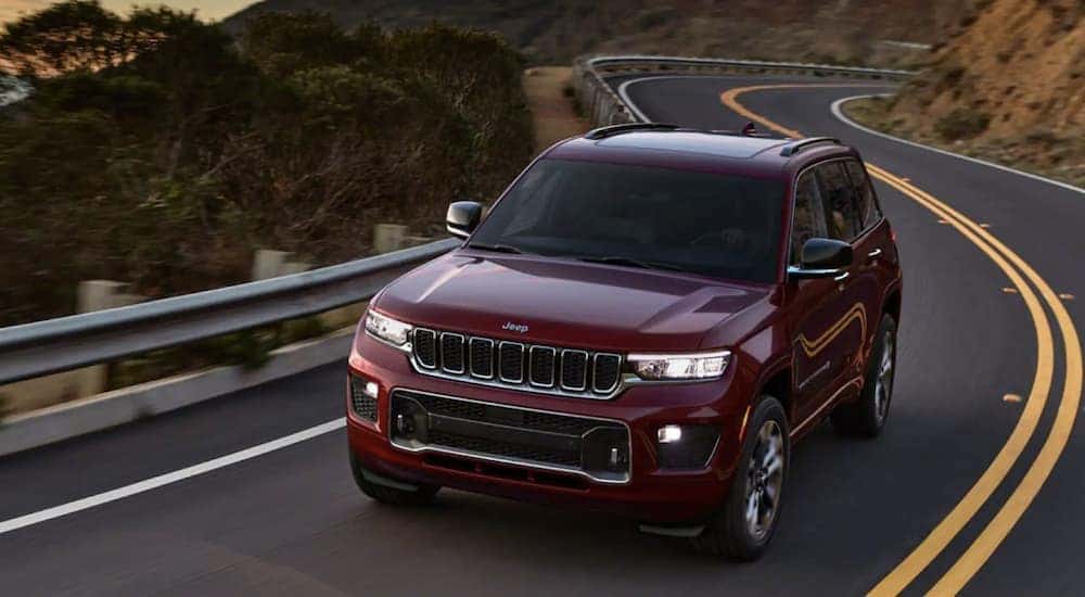 A red 2022 Jeep Grand Cherokee WL is shown driving from a dealer with used SUVs for sale near Troy.