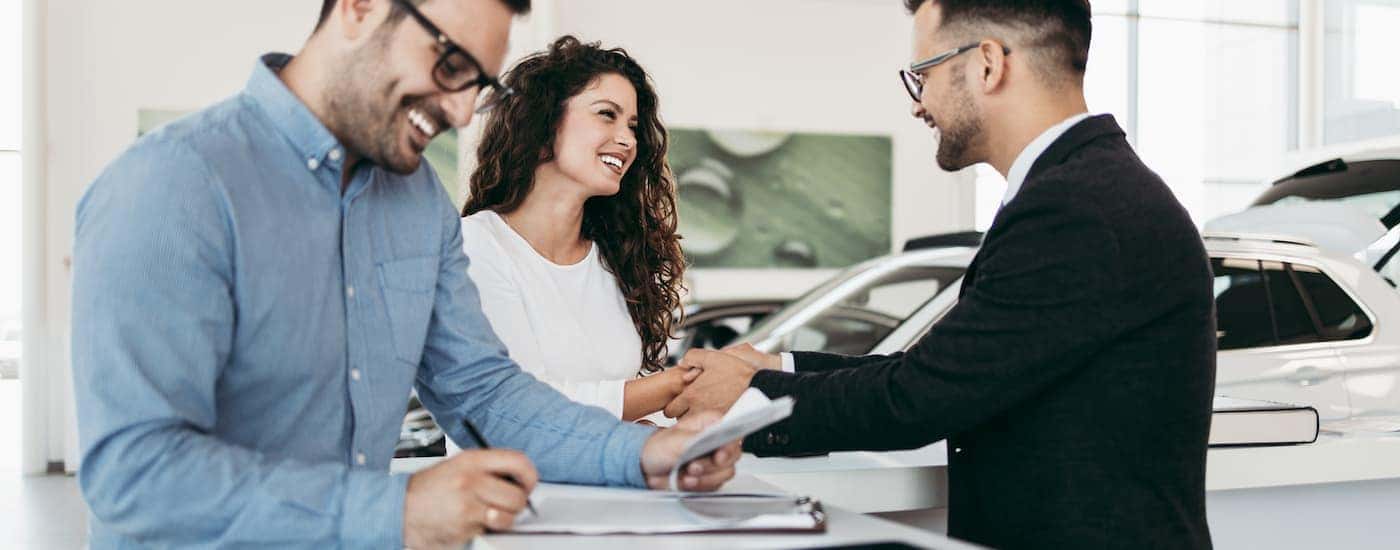 A salesman is helping a car buyer fill out paperwork on a trade-in.