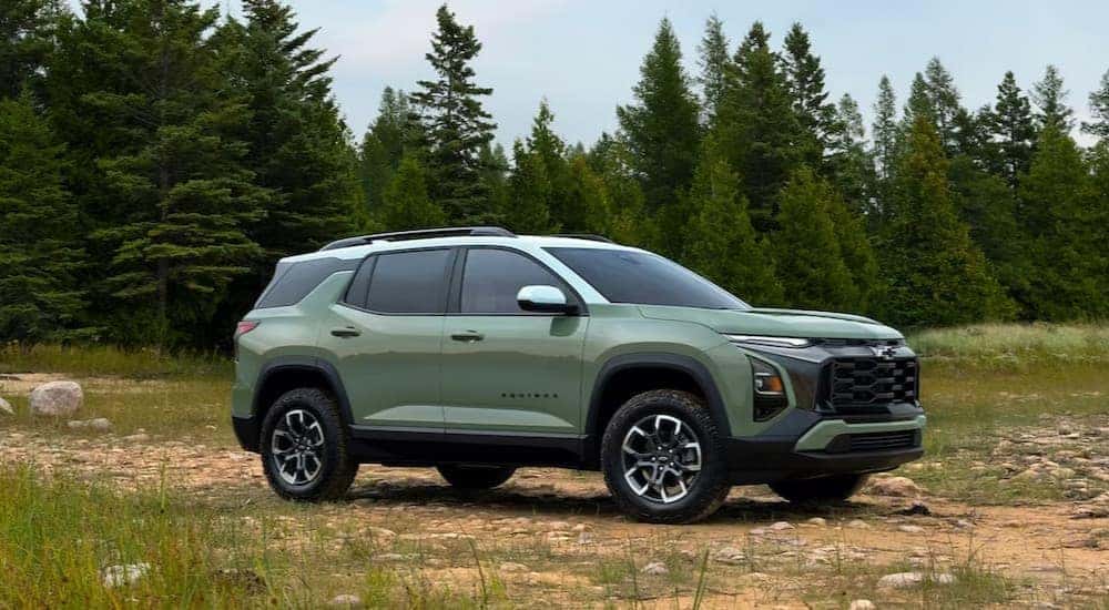 A green 2025 Chevy Equinox is shown parked off-road.