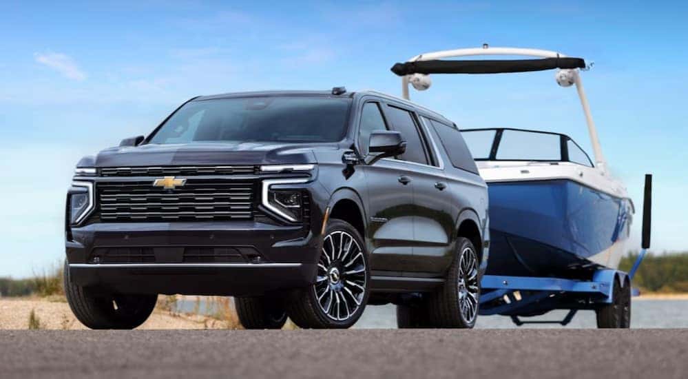 A blue 2025 Chevy Suburban is shown towing a boat.