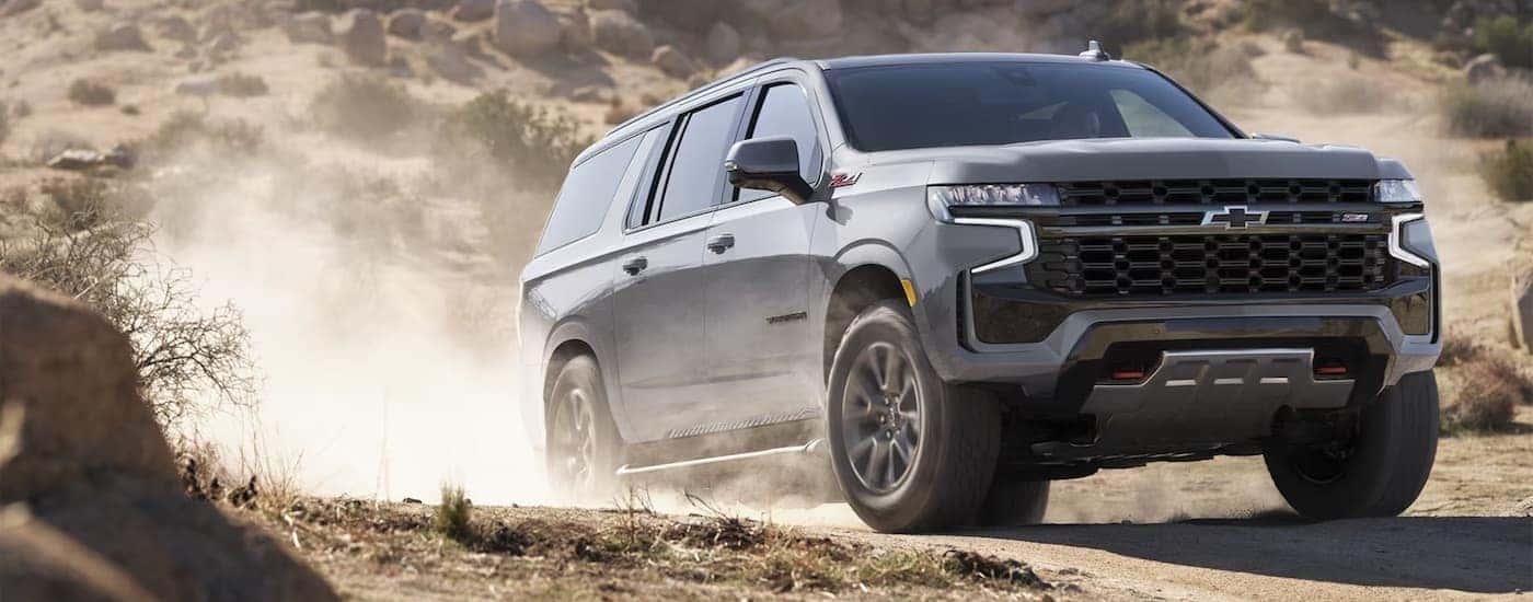 A grey 2024 Chevy Suburban Z71 is shown driving off-road after visiting a Chevy dealer near Rensselaer.