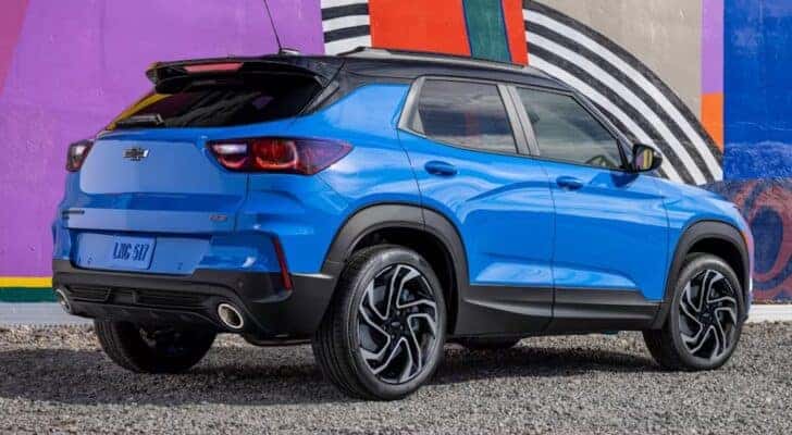 A blue 2024 Chevy Trailblazer is shown from behind while parked beside a wall.