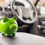 A green piggy bank is sitting on the center console of a vehicle.