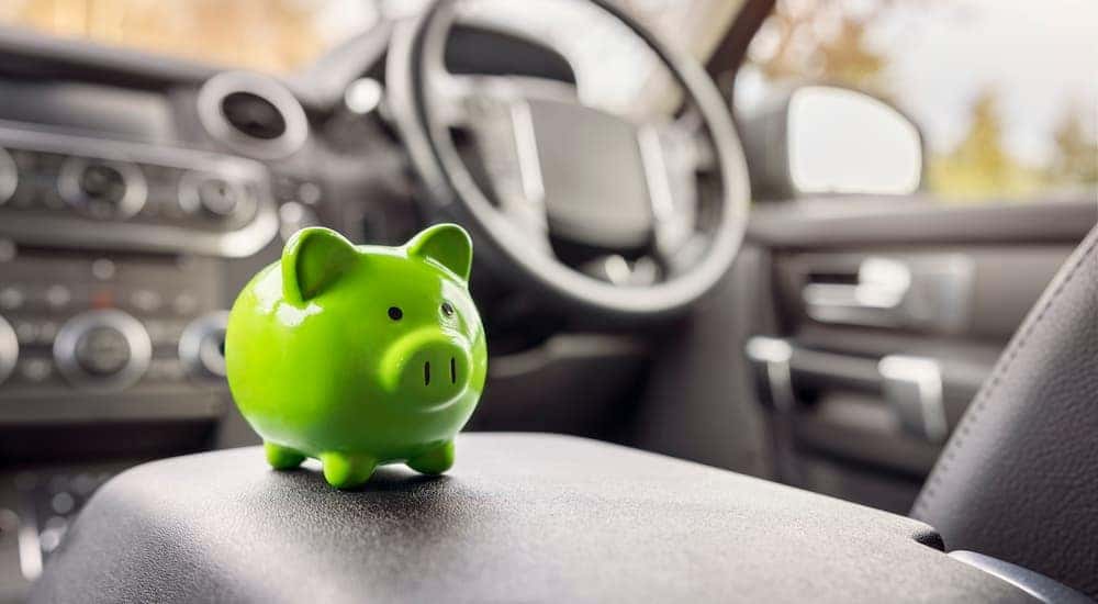 A green piggy bank is sitting on the center console of a vehicle.