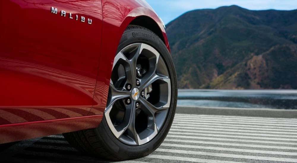 The front wheel of a red 2024 Chevy Malibu RS is shown in close-up.