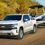 A white 2021 Chevy Silverado 1500 High Country towing a boat.