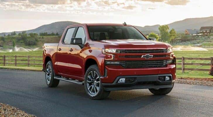 A red 2021 Chevy Silverado 1500 is shown parked near a ranch.