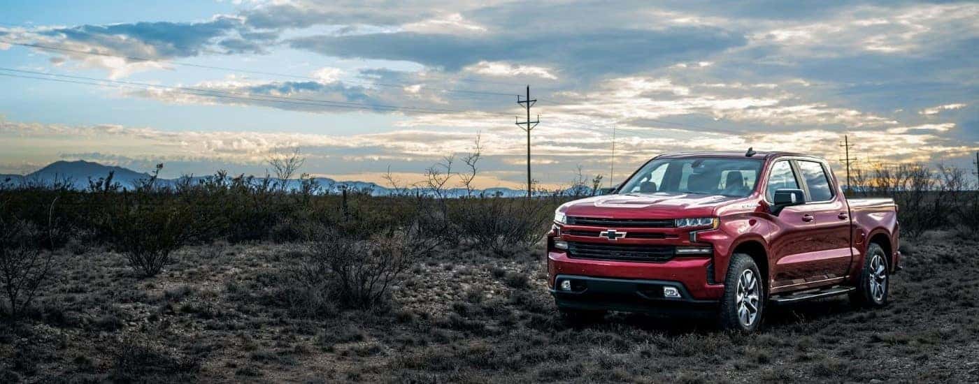 A red 2023 Chevy Silverado 1500 RST is shown parked near a field.