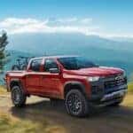 A red 2024 Chevy Colorado is shown driving off-road.