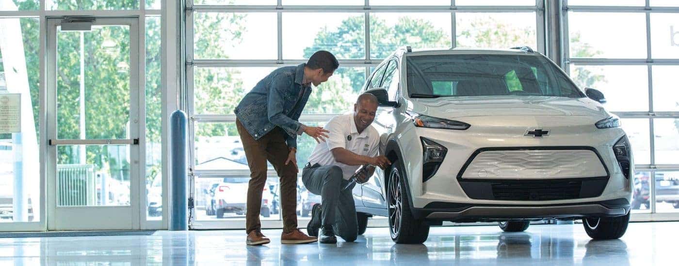 People are shown at a dealership inspecting a silver 2023 Chevy Bolt EUV.