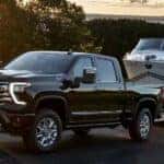 A black 2024 Chevy Silverado 1500 High Country is shown towing a boat.