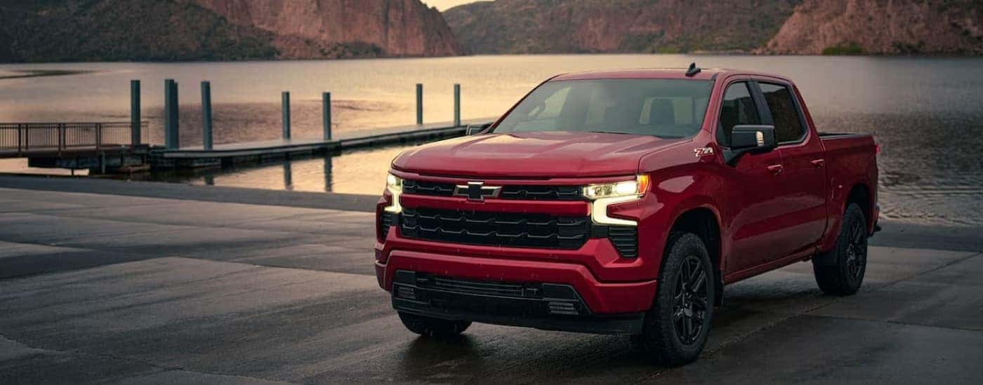 A red 2024 Chevy Silverado 1500 RST is shown parked near a dock.