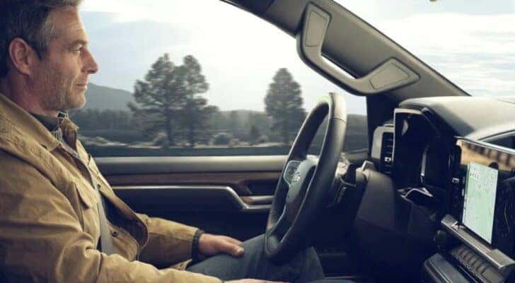 A person is shown using SuperCruise in a 2024 Chevy Silverado for sale in Albany.