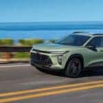 A green 2024 Chevy Trax is driving on an open road.