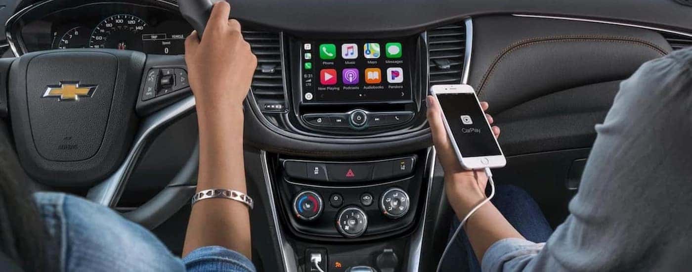 Buyers testing the Apple CarPlay feature in a 2020 used Chevy Trax for sale.