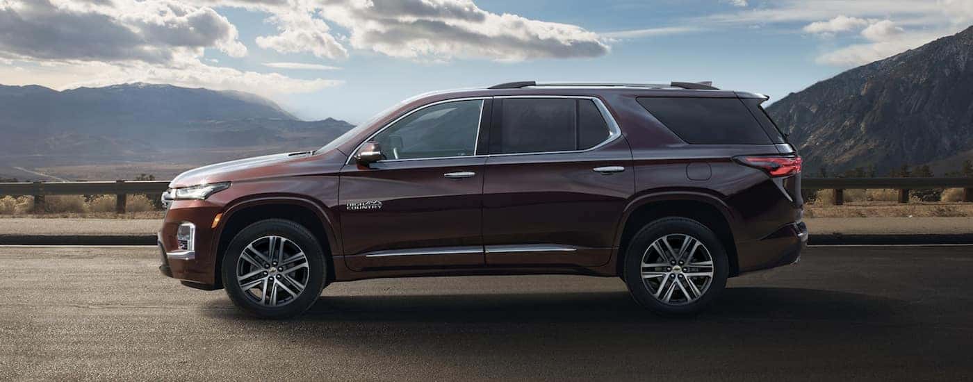 A copper 2022 Chevy Traverse High Country is shown driving near a mountain range.