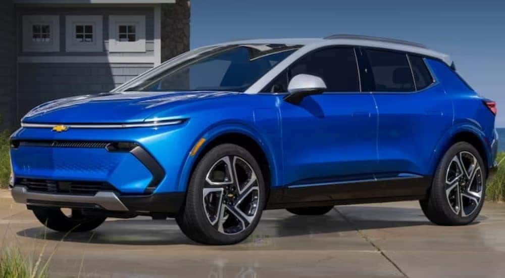 A blue 2024 Chevy Equinox EV is shown parked near a beach house.
