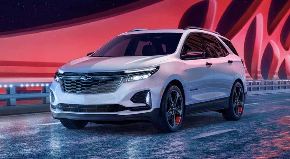 A white 2024 Chevy Equinox Redline Edition is shown driving after viewing a Chevy Equinox for sale in Albany.