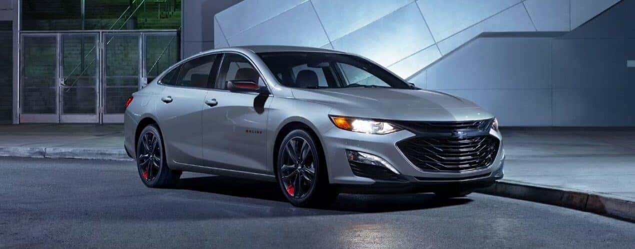 A silver 2024 Chevy Malibu Redline is shown parked near a curb.