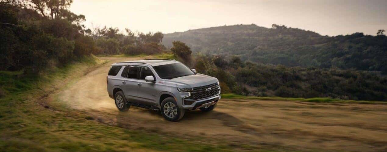 A silver 2024 Chevy Tahoe Z71 is shown driving off-road.
