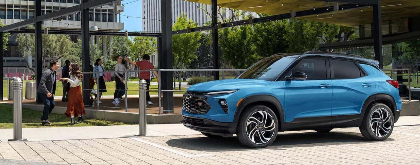 A blue 2024 Chevy Trailblazer RS is shown parked near people dancing.