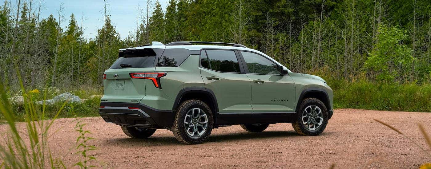 A rear view of a green 2025 Chevy Equinox ACTIV parked off-road.