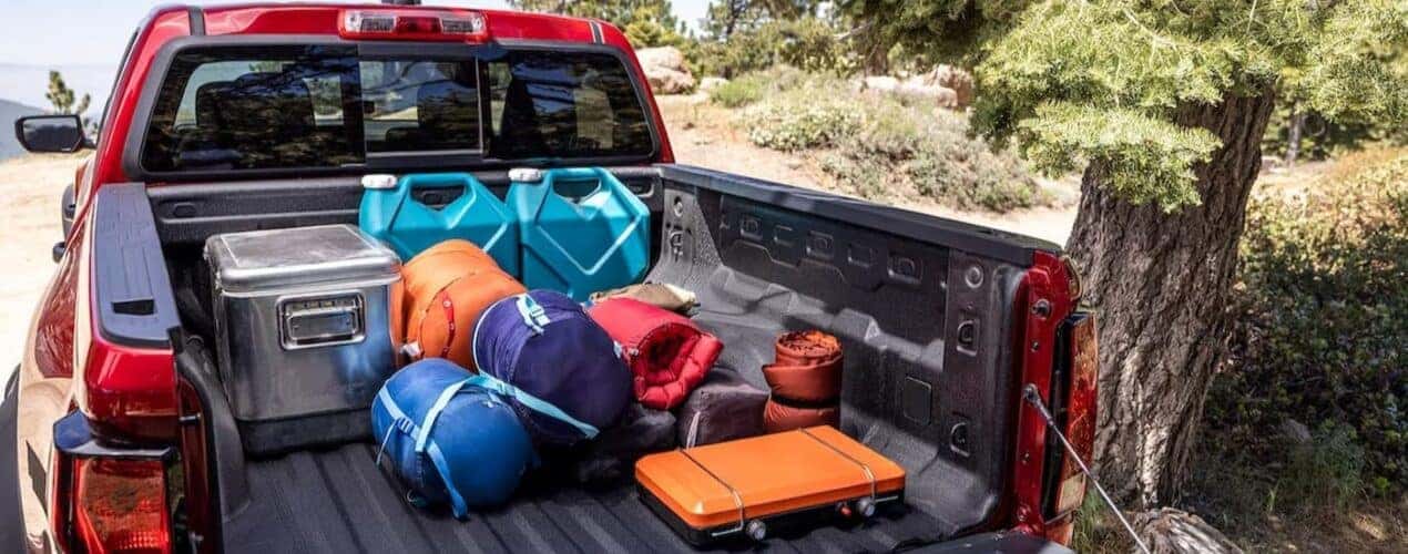 Camping gear is shown in the bed of a red 2024 Chevy Colorado Trail Boss.