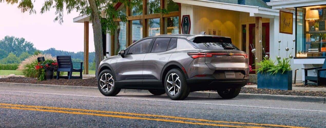A silver 2024 Chevy Equinox EV is shown parked near a store.