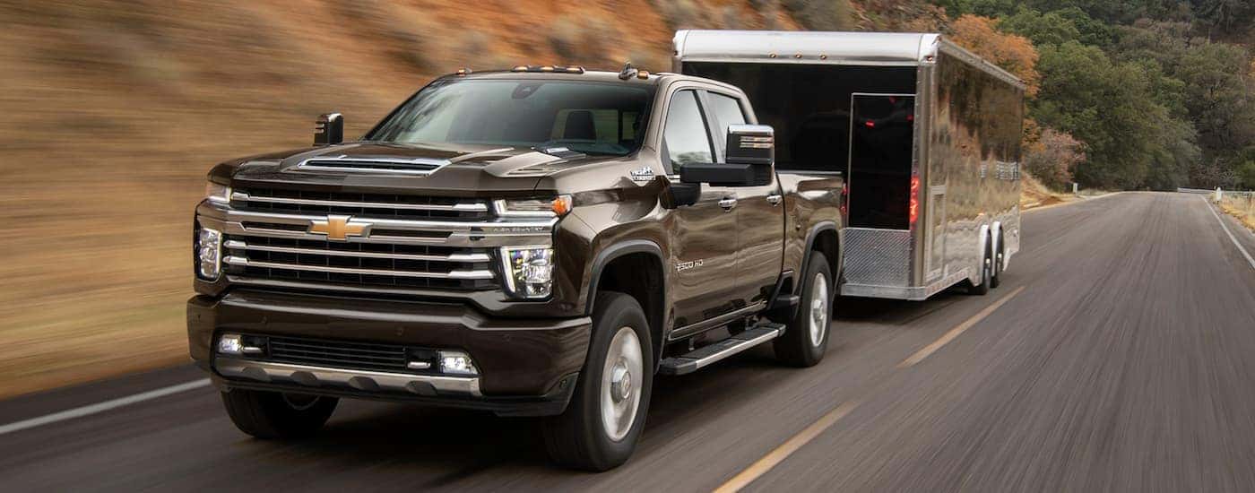 A black 2021 Chevy Silverado 2500 HD High Country towing a trailer.