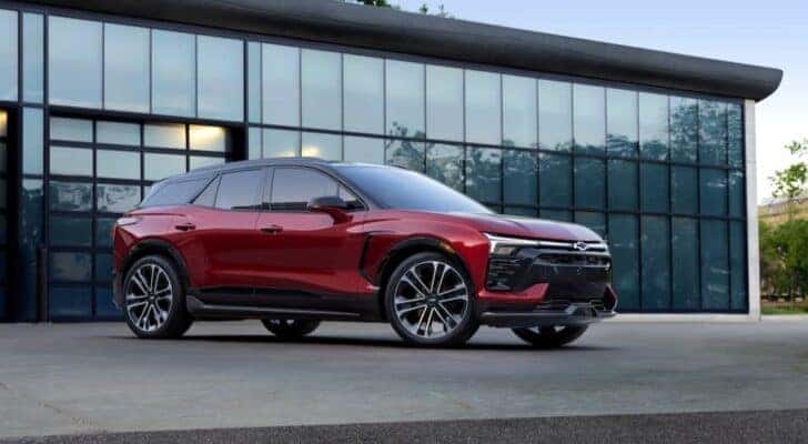 A red 2024 Chevy Blazer RS EV is shown parked near a glass building.