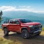 A red 2024 Chevy Colorado Trail Boss is shown driving off-road.