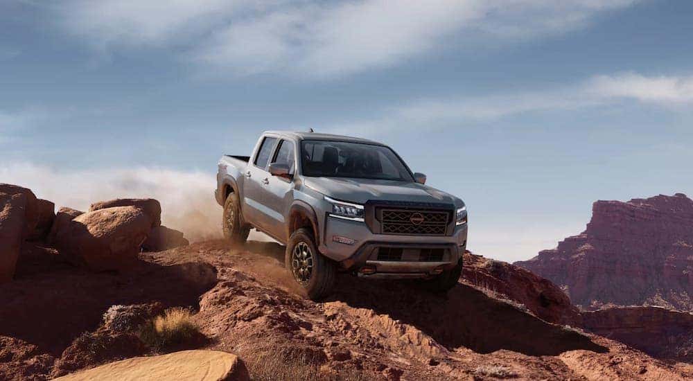 A grey 2024 Nissan Frontier driving down a rocky hill.