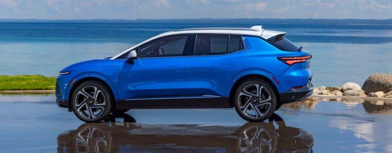 A blue 2025 Chevy Equinox EV LT is shown parked near an ocean.