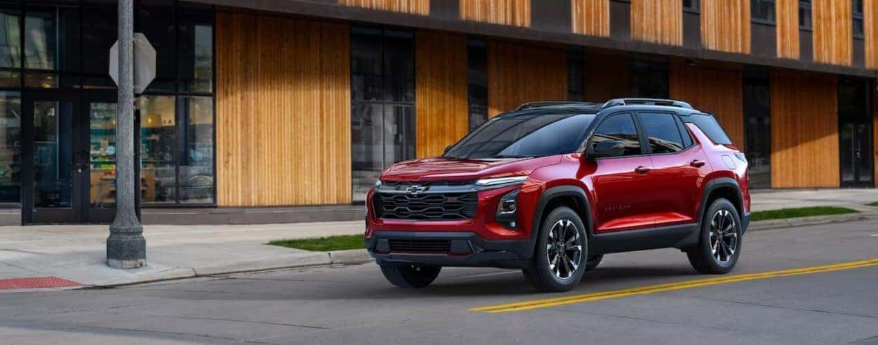 A red 2025 Chevy Equinox RS is shown stopped on a city street.