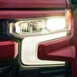 Close-up of the headlight on a red 2023 used Chevy Silverado for sale in Albany.
