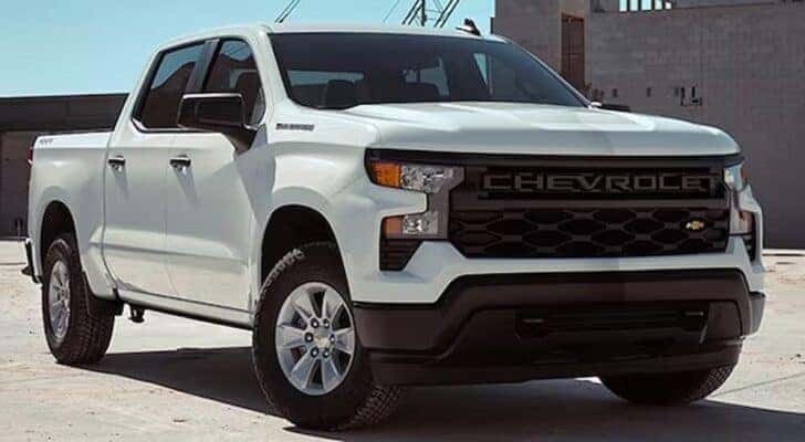A popular Chevy Silverado for sale in Albany, a white 2024 Chevy Silverado 1500 WT, is shown parked on a sunny day.