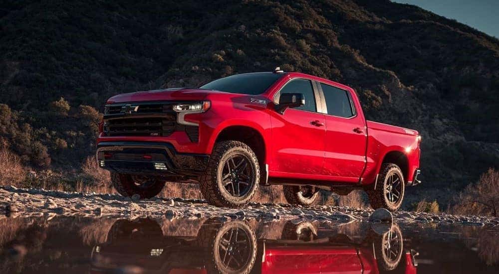 A red 2023 Chevy Silverado Z71 Trail Boss is shown from the front at an angle after leaving a dealer that has a used Chevy for sale.