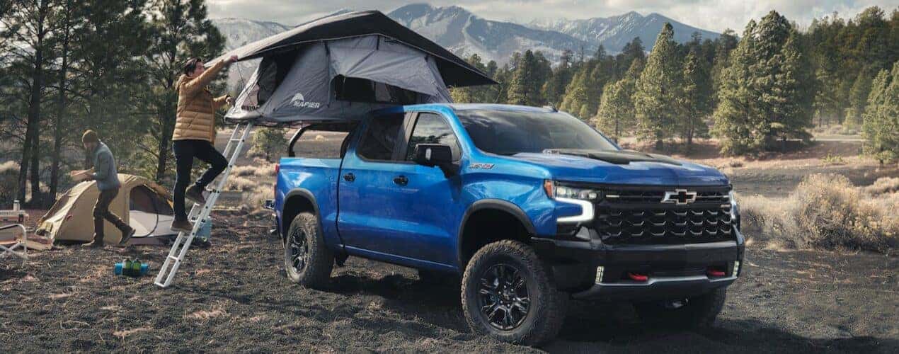 A blue 2025 Chevy Silverado 1500 ZR2 is shown parked on a campsite.
