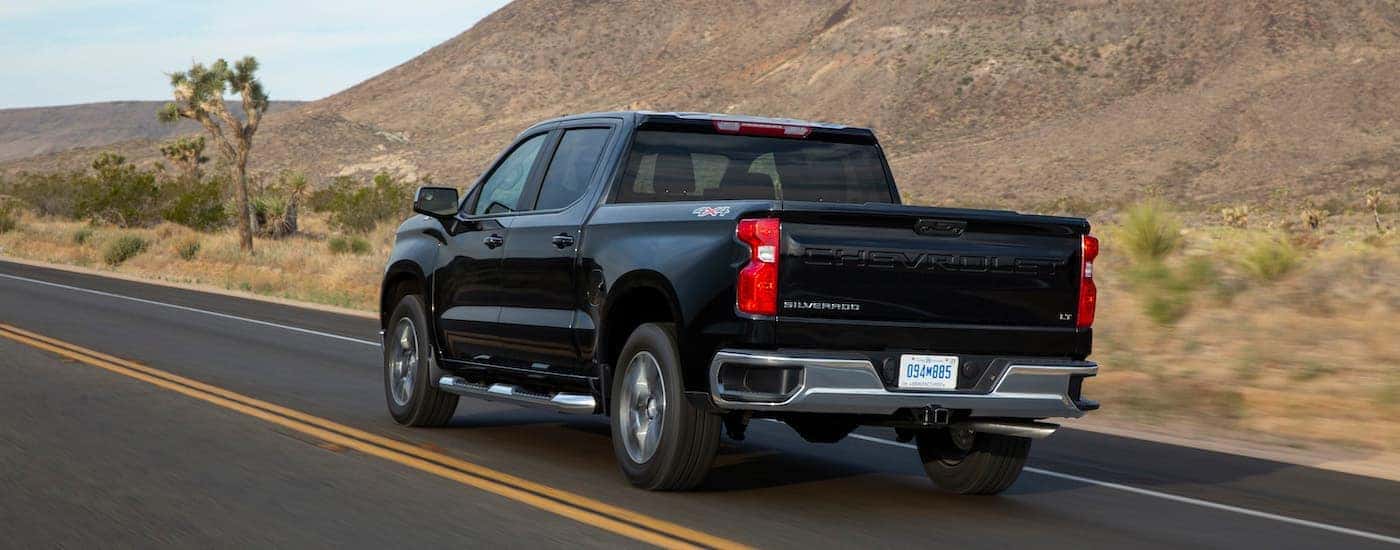 A black 2024 Chevy Silverado 1500 LT is shown from the rear at an angle.