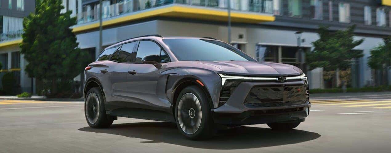 A gray 2025 Chevy Blazer EV RS is shown driving on a city street.