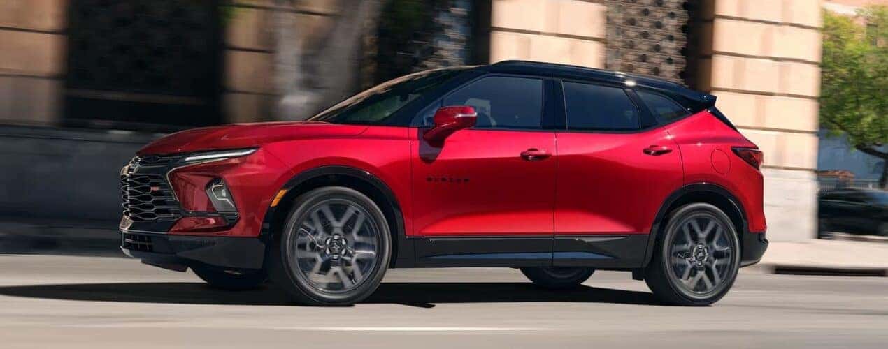 A red 2025 Chevy Blazer RS is shown driving on a city street.