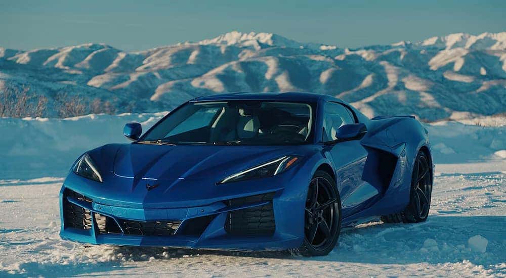 A blue 2025 Chevy Corvette E-Ray parked off-road on snowy terrain.