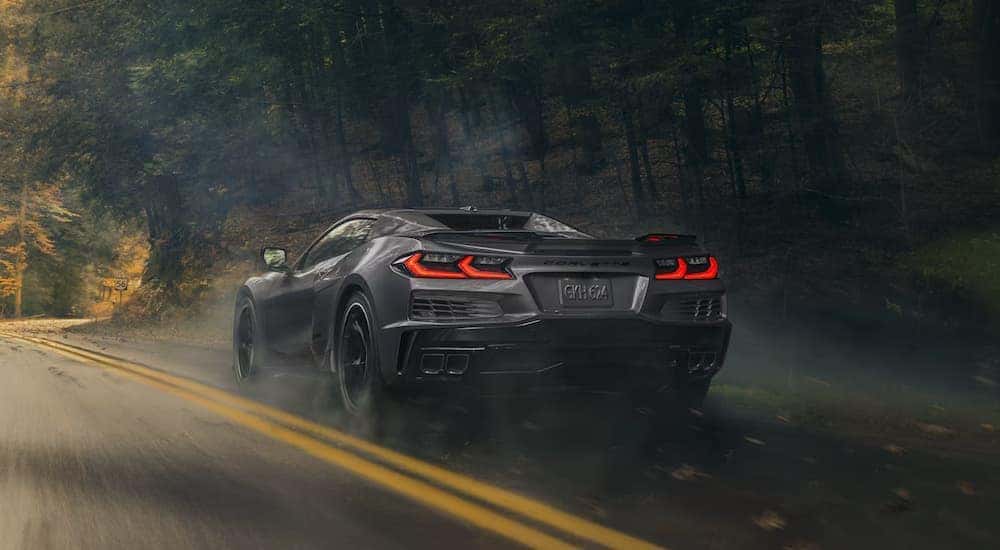 Rear view of a grey 2025 Chevy Corvette E-Ray driving down a road.