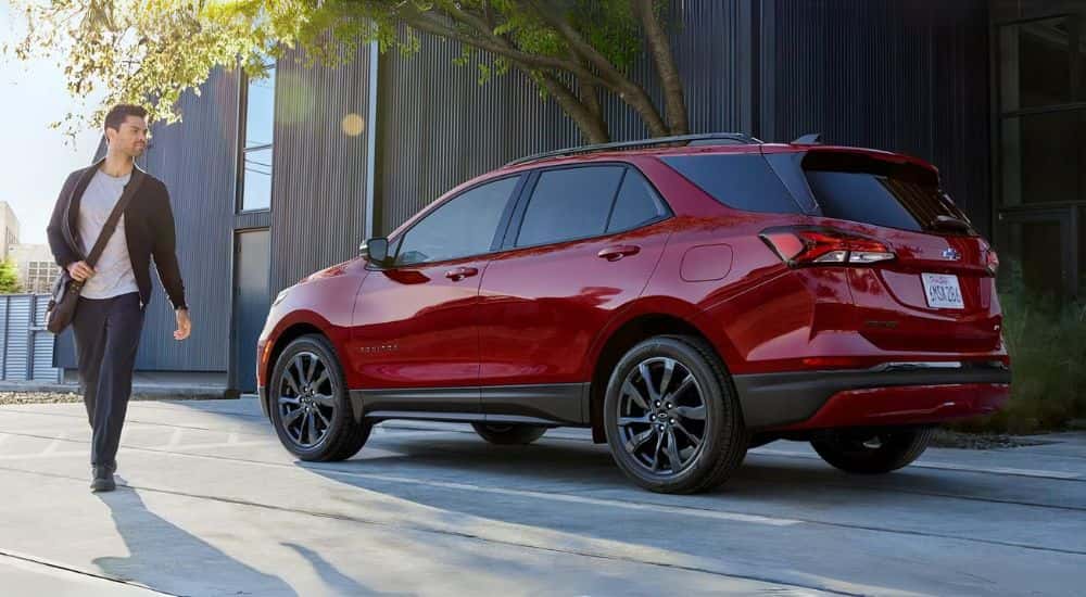 A red 2023 Chevy Equinox RS is shown parked near a person walking.