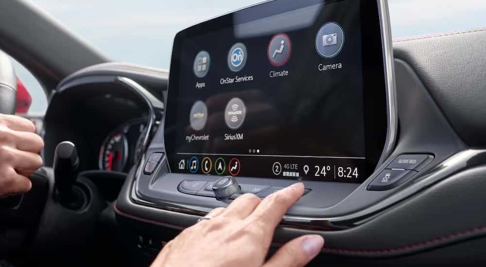 A close-up of a hand touching the infotainment screen is shown in a 2025 Chevy Blazer.
